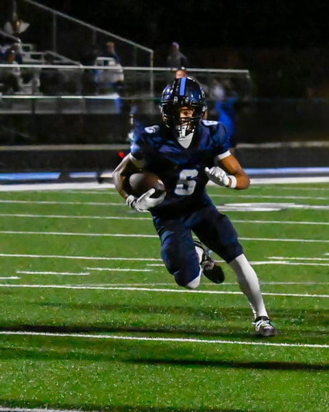 A high school football player on the run as he approaches the goal line late in the game