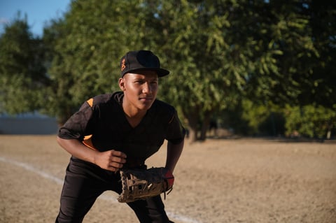Young male baseball player wearing uniform and glove, ready to field a play