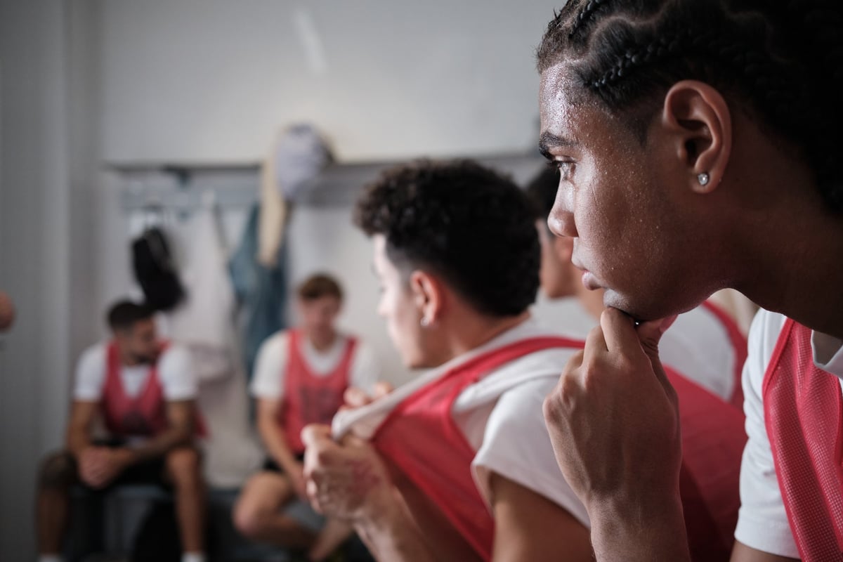 Young male athlete in uniform listening intently, reflecting on game strategy with his teammates