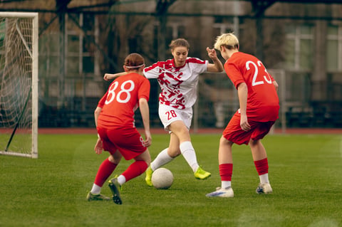 Women soccer players play football.